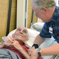 Lowry visits with a patient who is lying in bed